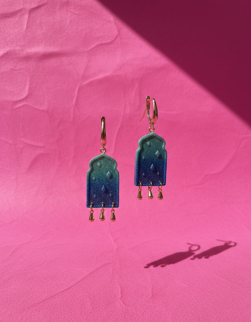 A pair of  Teal to blue ombre earrings adorned with tear drop gold plated charms 