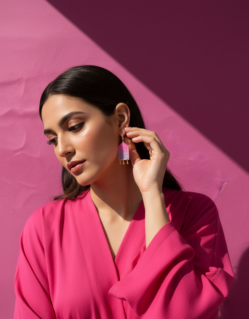 Woman wearing ombre pink earrings against a pink background